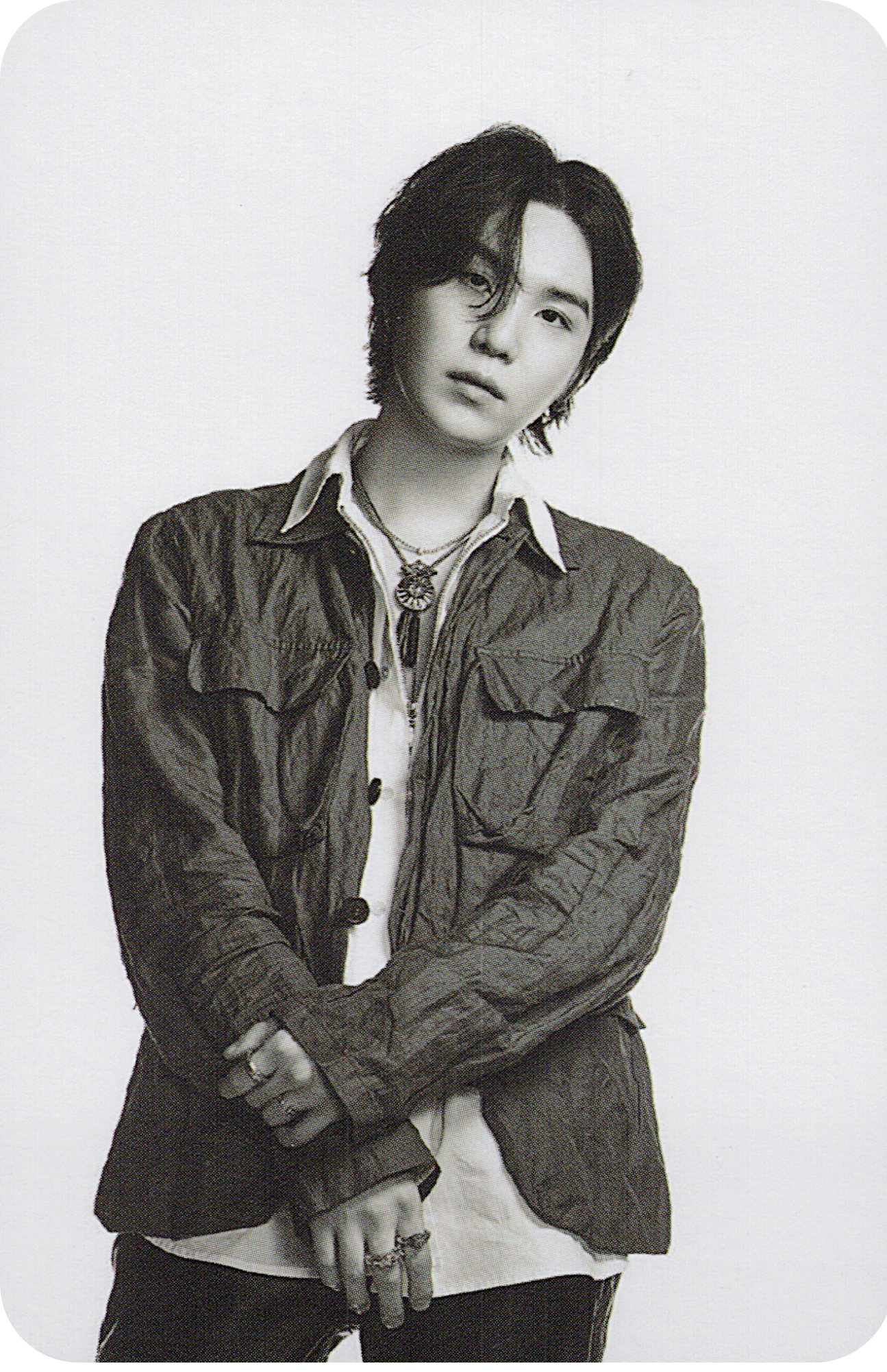 Black and white photo of BTS member Suga wearing a jacket with a necklace.