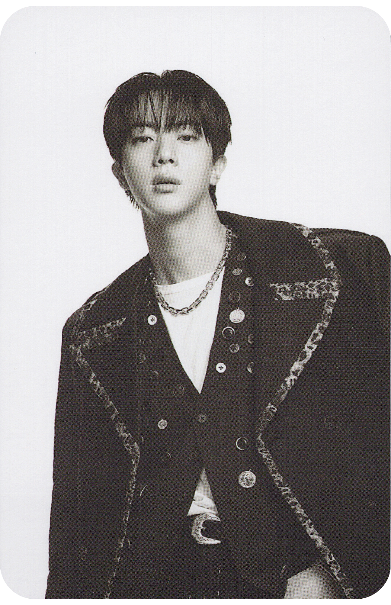 BTS member Jin wearing a stylish black jacket with decorative elements on a white background