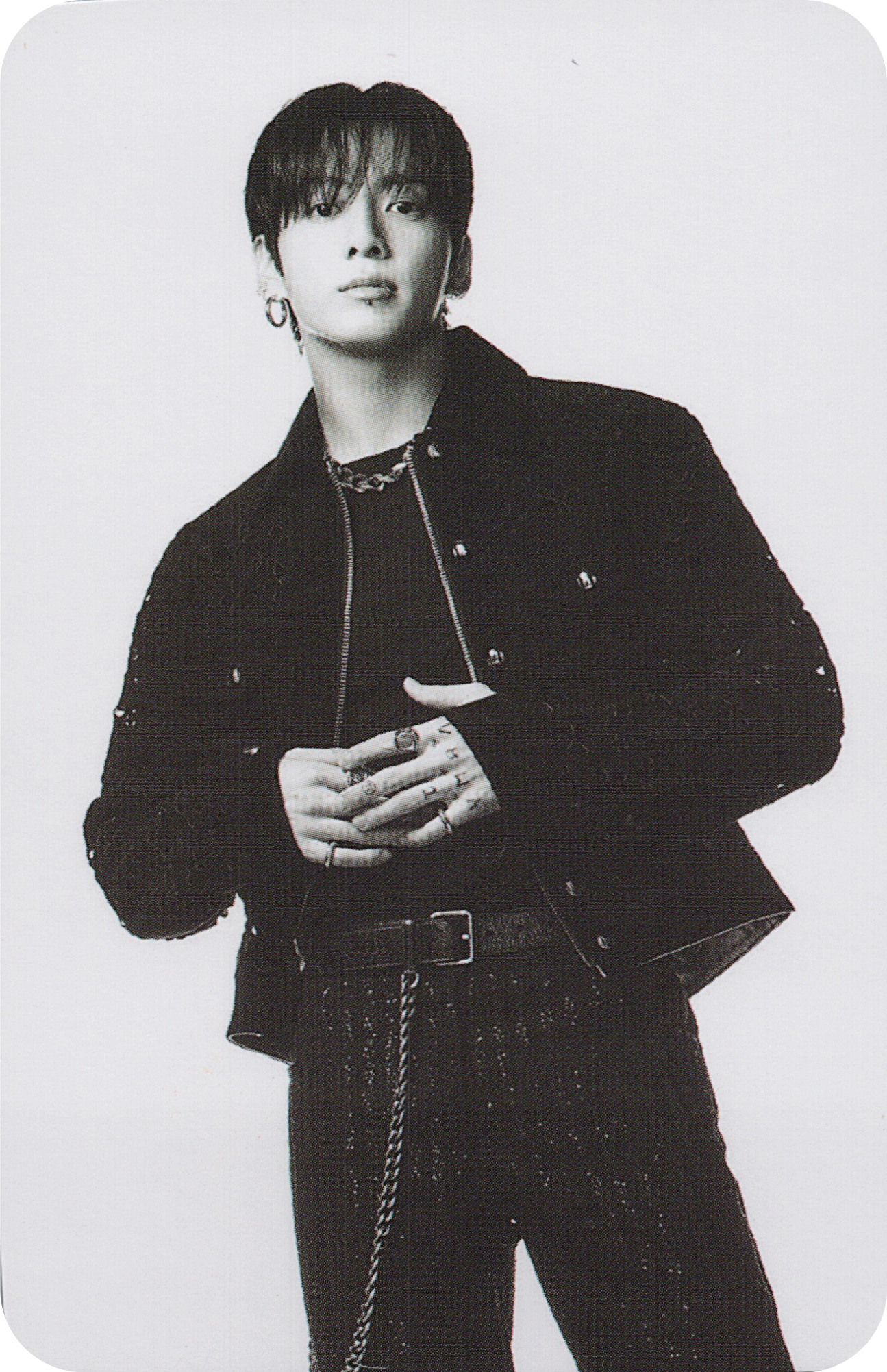 Black and white photo of BTS member Jungkook wearing a jacket and pants with a chain detail.