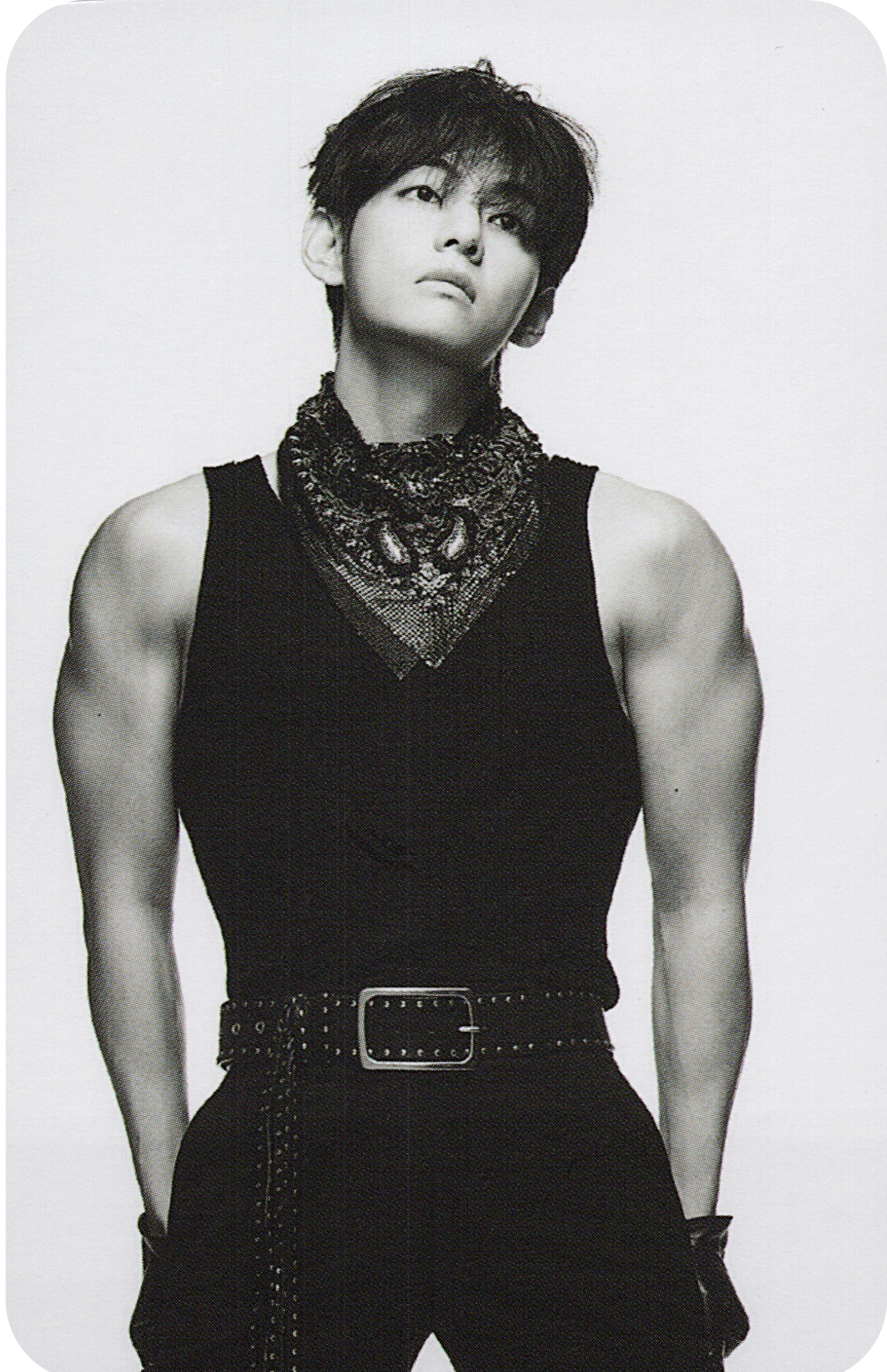 Black and white portrait of BTS member Taehyung wearing a sleeveless top with a decorative belt.