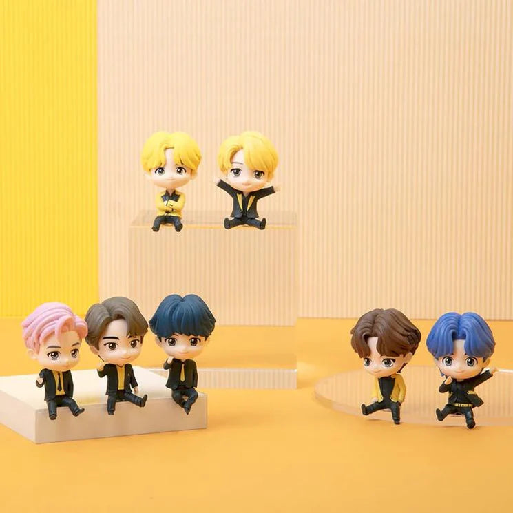 Set of small BTS TinyTAN figurines with different hairstyles on a yellow background