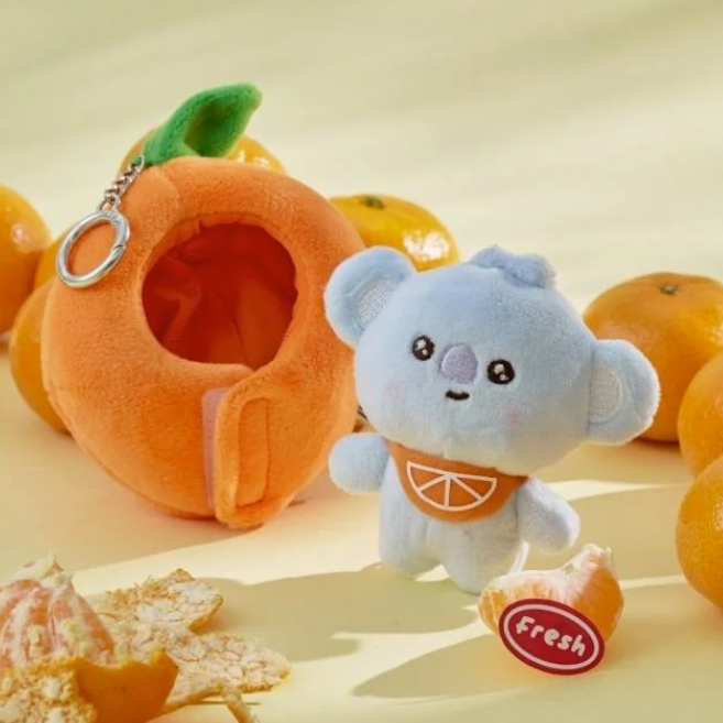 BTS BT21 Koya Plush toy koala with an orange outfit surrounded by tangerines on a light background