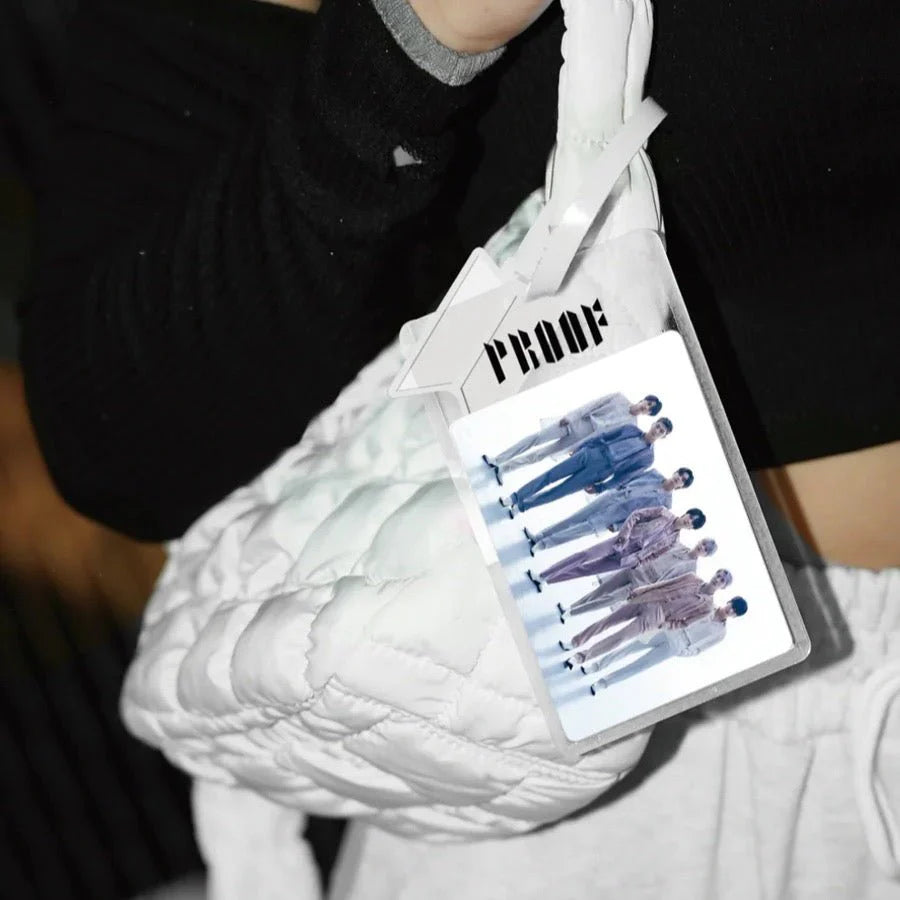 White quilted handbag with a card holder featuring a BTS graphic design, held by a person.