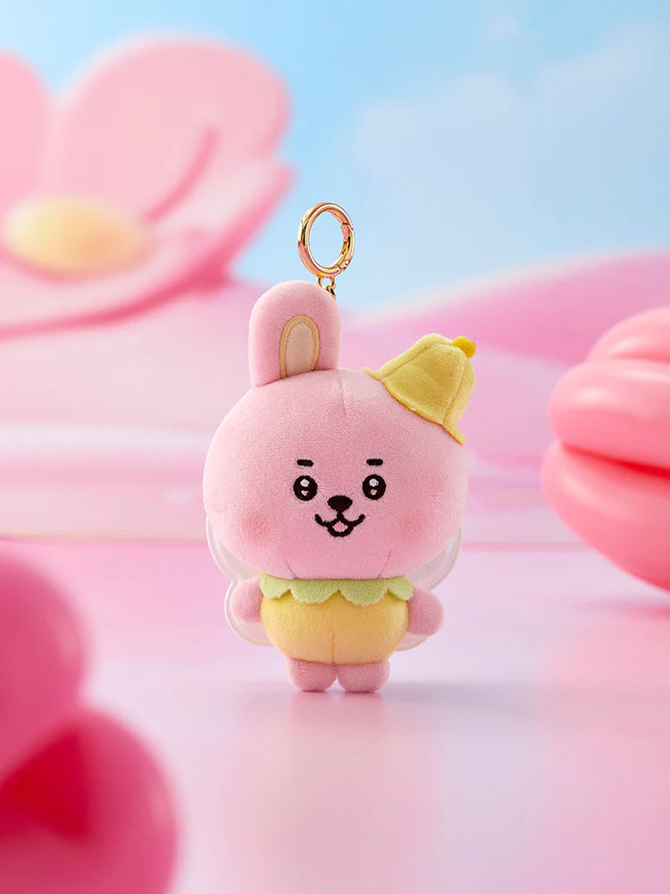 Plush BTS BT21 Cooky keychain shaped like a spring fairy cartoon character with pink hair and yellow outfit against a soft pink and blue background.