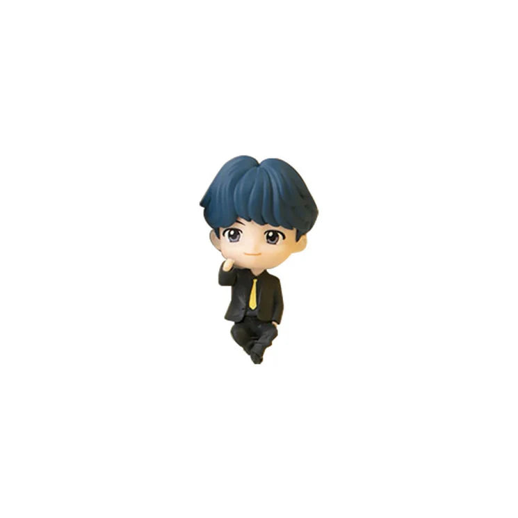 Small figurine of a BTS TinyTAN Suga character with blue hair and a black suit on a white background